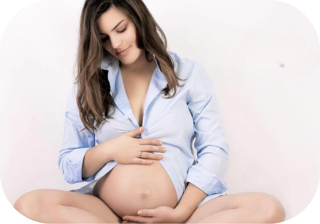 Photo représentant une femme enceinte en fin de grossesse qui regarde et touche son ventre.